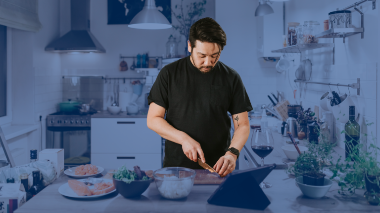 a man in a home kitchen cutting a piece of meat